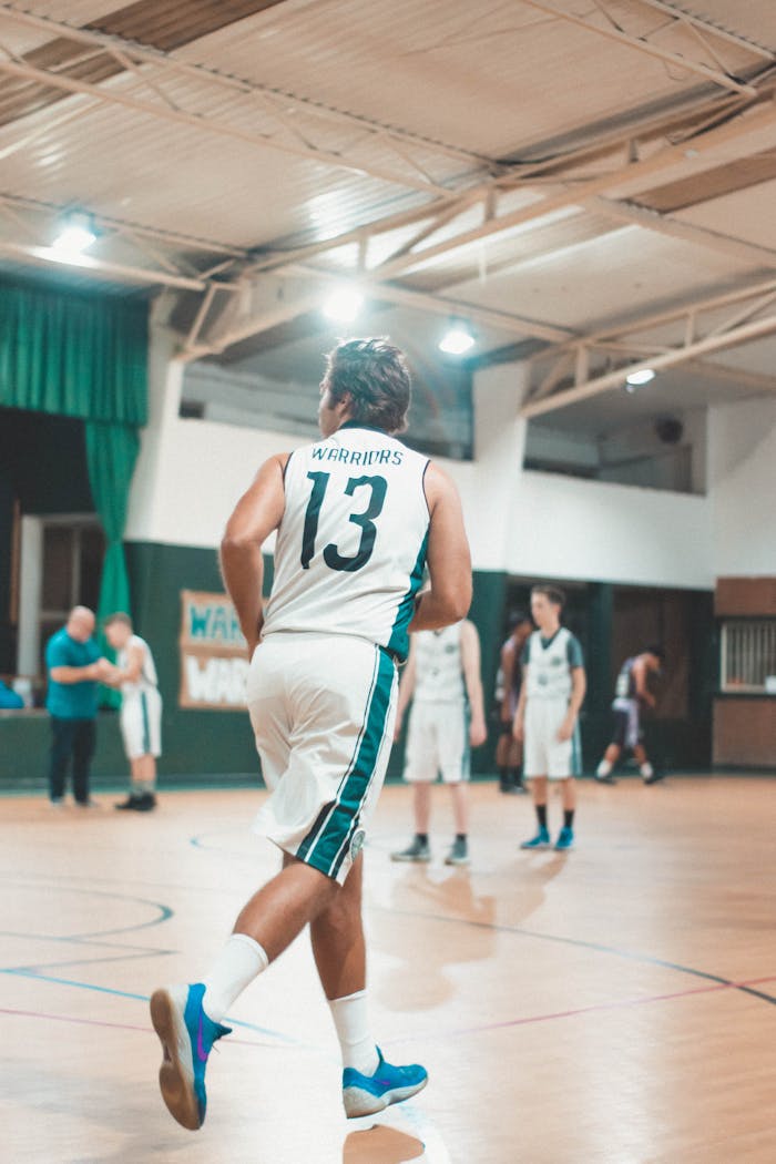 gallery-4 Dynamic indoor basketball scene with players in action and team uniform.