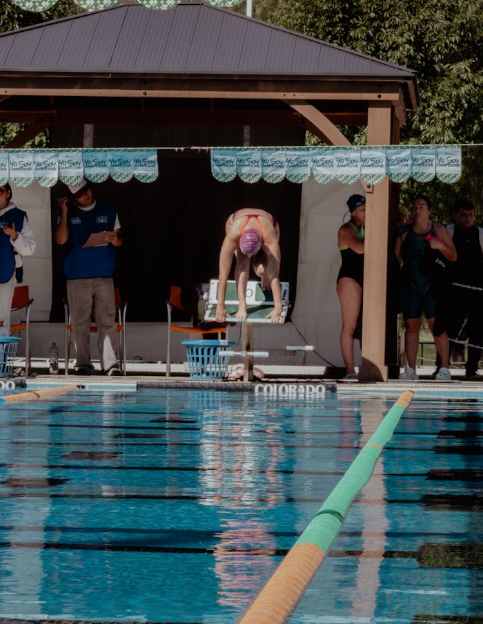 why-choose-us Swimmer dives into outdoor pool during competition in Aguascalientes, Mexico, showing athletic skill.