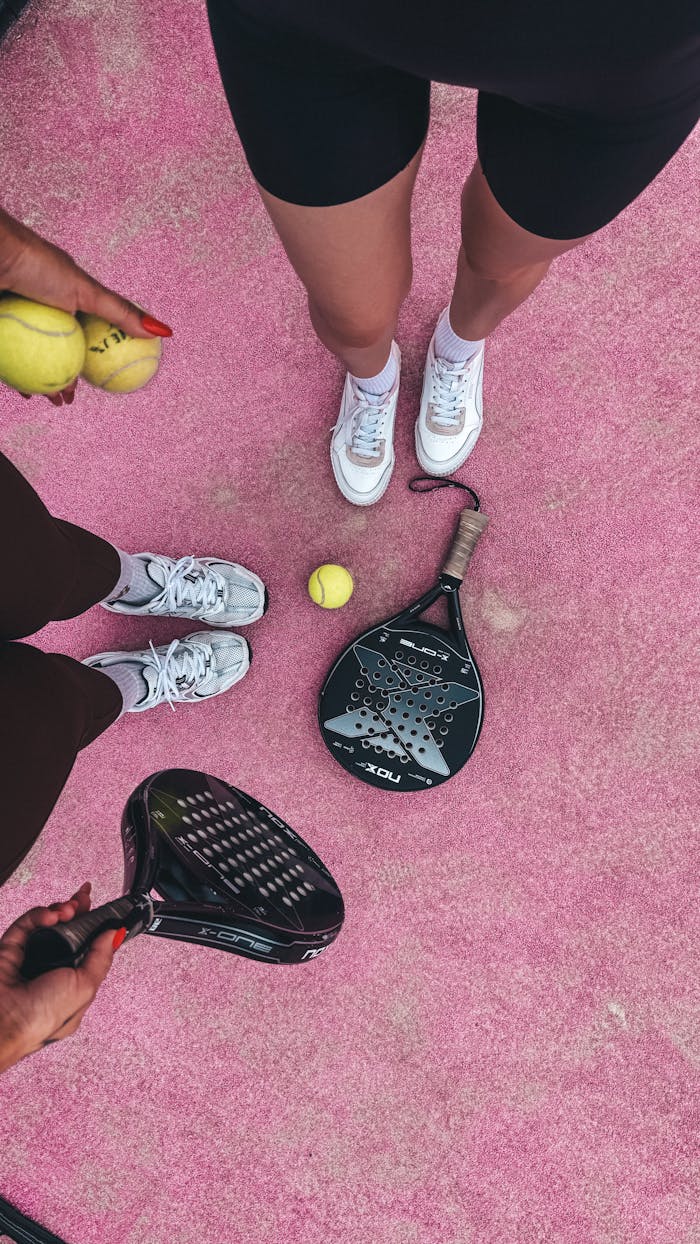 about-02 Padel players with rackets and tennis balls on a vibrant pink court, ready to play.
